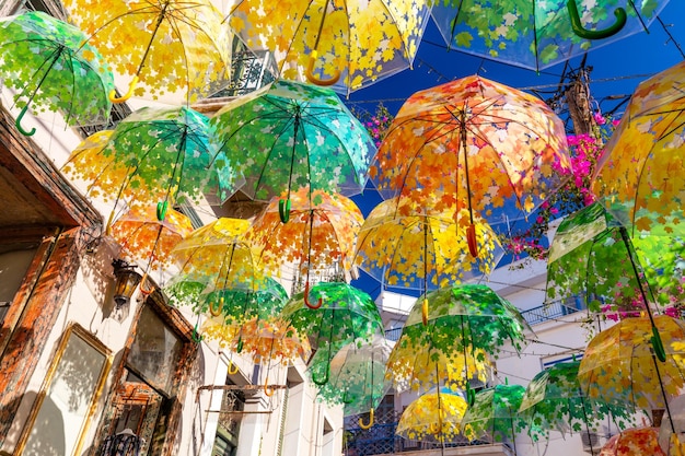 Street decorated with umbrellas of different colours in old town on summer sunny day Aegina island Greece Europe