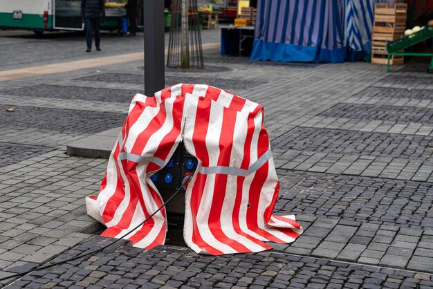Street electricity distributor covered with red and white striped tarpaulin