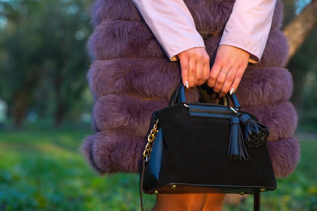 Foto concetto di moda di strada. donna vestita alla moda che tiene la borsa della pelle scamosciata nera. spazio vuoto