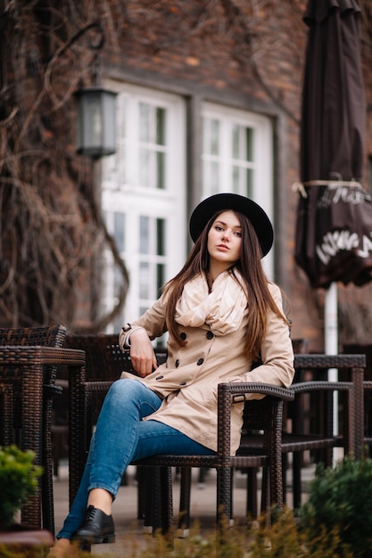 Street fashion concept Vintage portrait of young woman in spring coat and hat Flattering hair