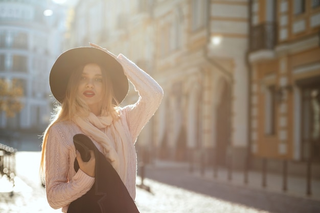 Street fashion concept: vrij jong meisje met hoed en trui poseren met schittering van de zon. Ruimte voor tekst