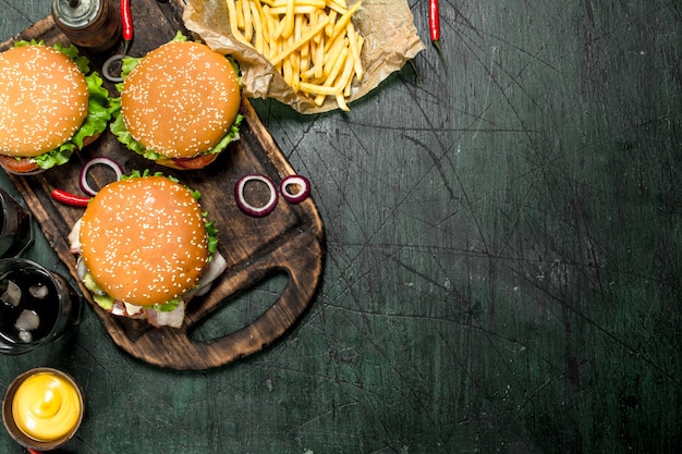 Street food. Burgers with fries and cola. On a rustic table.