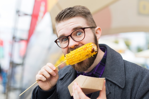 Street food and cuisine concept - Man eating grilled corn. Vegetarian food. healthy and tasty vegetables.