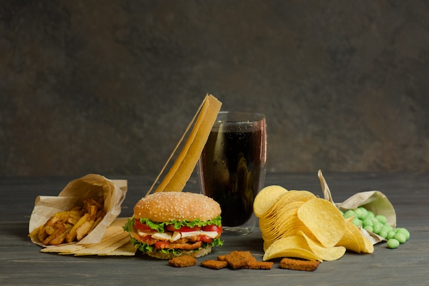 Street food or fast food. Hamburger, french fries and cola on table with wooden table. Unhealthy burger with beef.