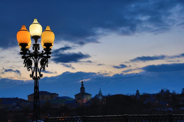 Lampione sullo sfondo di un bel cielo al tramonto con nuvole case colorate e chiesa