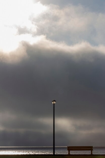 Street lamp and bench in front of the dramatic clouds sky background