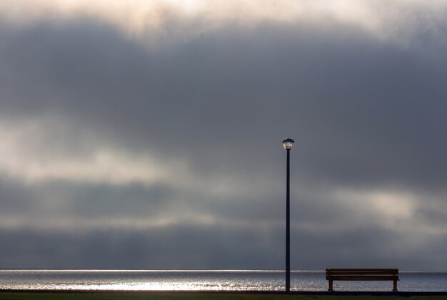 Street lamp and bench in front of the dramatic clouds sky background