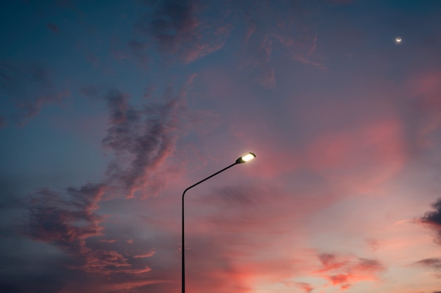 Street light pole with the moon and colorful evening sky