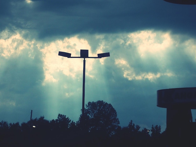 street light and treetops against cloudy sky