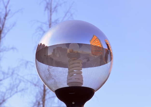 Street lighting lamp on a blue sky Round glass ball with spiral energysaving light bulb