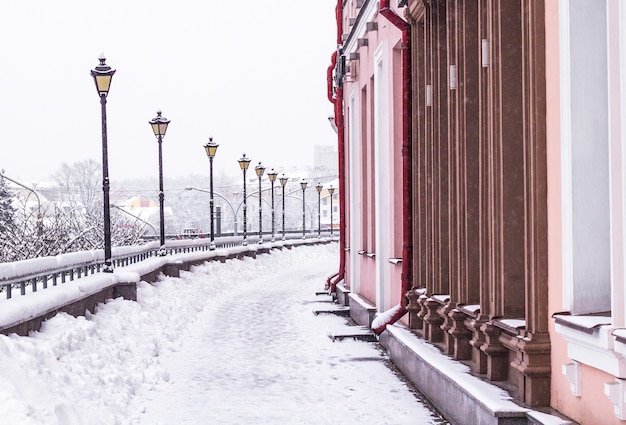 Уличные фонари вдоль заснеженной улицы города зимой