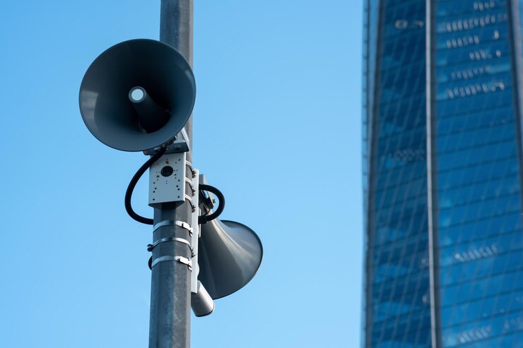 street loudspeakers on a pole against the background of a glass facade of a modern building