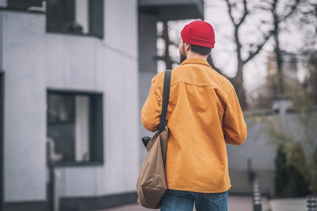 In the street. Man in an orange jacket walking down the street