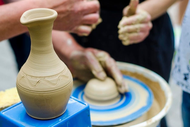 Street master class on modeling of clay on a potter's wheel in
the pottery workshop focus on the vase the process of making the
vase blurred against the background