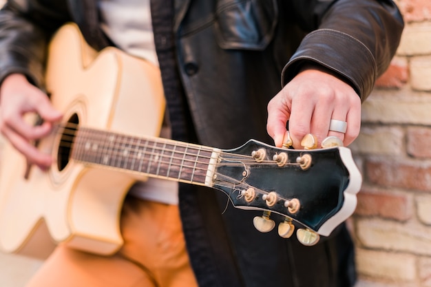 Street musician close up tuning the guitar Fingers turning the tuning pegs of an acoustic guitar