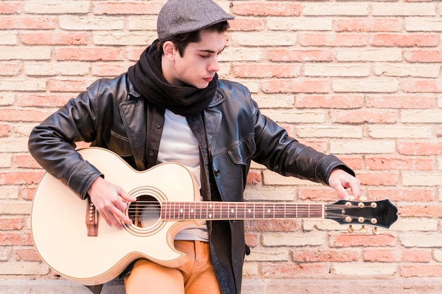 Street musician tuning the guitar Fingers turning the tuning pegs of an acoustic guitar