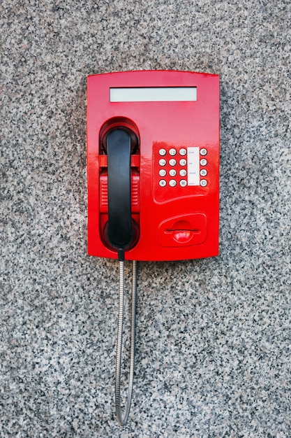 Street pay phone red on the wall.