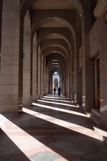 Street photo of people walking on hallway with sun shadow