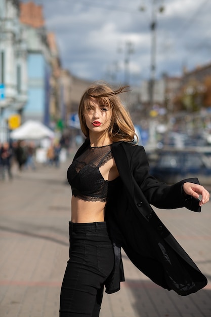 Street portrait of amazing woman with long hair wears lingerie and jacket posing with strong wind