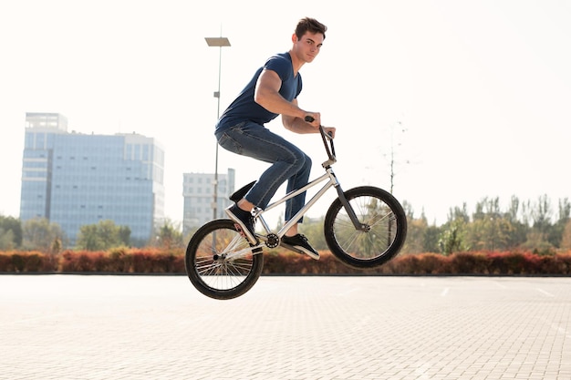 Уличный портрет гонщика bmx в прыжке на улице на фоне городского пейзажа