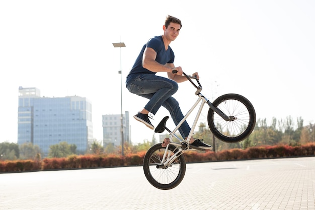 Ritratto di strada di un pilota di bmx in un salto per strada sullo sfondo del paesaggio della città