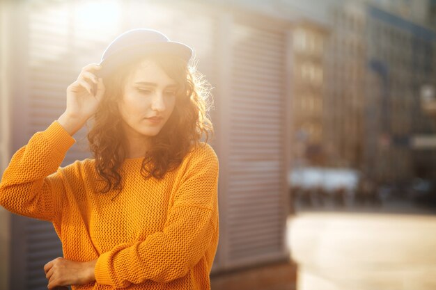 Street portrait of fabulous brunette model wearing trendy apparel posing in rays of sun. space for text