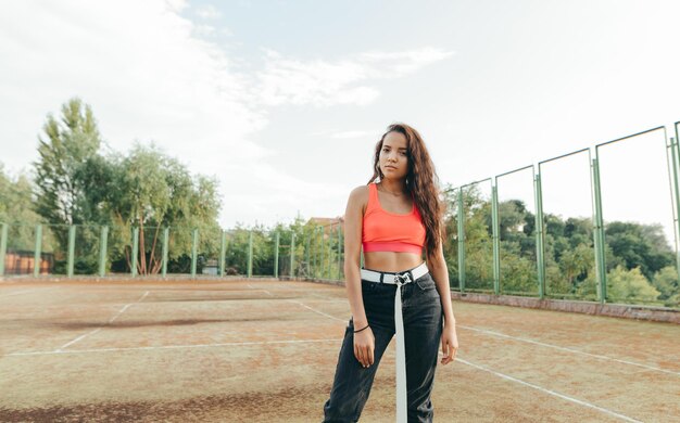 Street portrait of a stylish lady in roe deer stands on a basketball court and poses for the camera