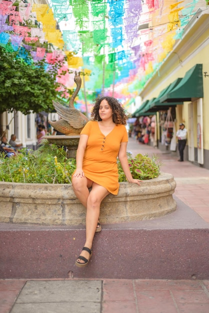 Street portrait of young woman looking at camera with multicolored flags in backgroundCurly hair