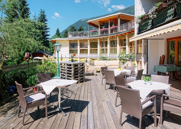 Street restaurant with tables and chairs at hotel resort in Bad Kleinkirchheim in Carinthia, Austria. Design of Sidewalk cafe. Lifestyle and nature. Terrace or veranda of cafe ready for breakfast