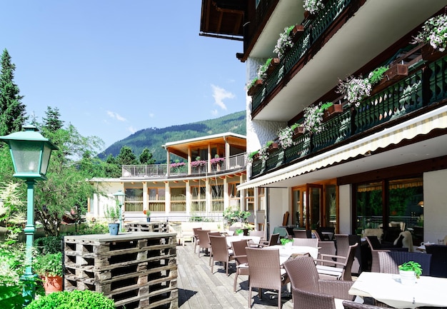 오스트리아 카린티아(Carinthia)의 바트 클라인키르히하임(Bad Kleinkirchheim)에 있는 호텔 리조트에 테이블과 의자가 있는 거리 레스토랑. 보도 카페의 디자인입니다. 라이프 스타일과 자연. 아침 식사 준비가 된 카페의 테라스 또는 베란다