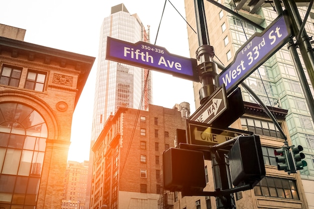 ニューヨーク市の日没時の5番街と西33丁目の道路標識-マンハッタンのダウンタウンの都市コンセプトと道路の方向-暖かく劇的なフィルター処理された外観のアメリカの世界的に有名な首都の目的地