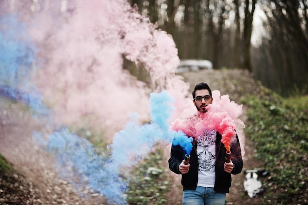 Street style arab man in eyeglasses hold hand flare with red and blue smoke grenade bomb