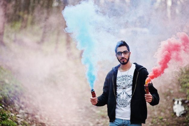 Street style arab man in eyeglasses hold hand flare with red and blue smoke grenade bomb