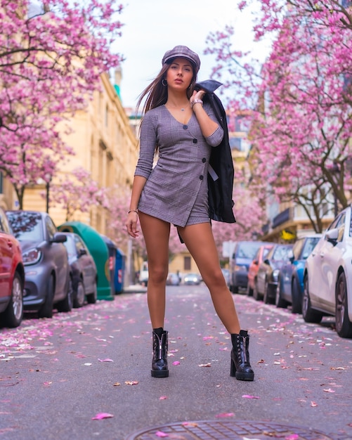 Street Style in the city, brunette Caucasian girl with leather jacket walking in the city with the blossomed trees in spring