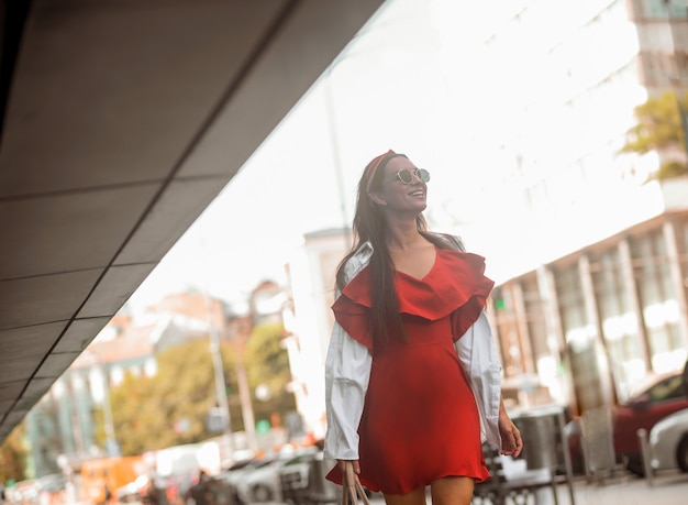 In the street. A stylish woman in a red dress walking down the street