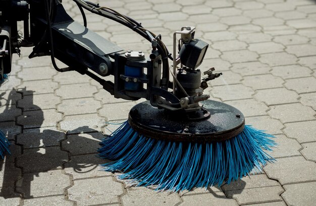 Street sweeper washing garbage from walkway and cleaning with rotating blue brushes. Concept clean streets.