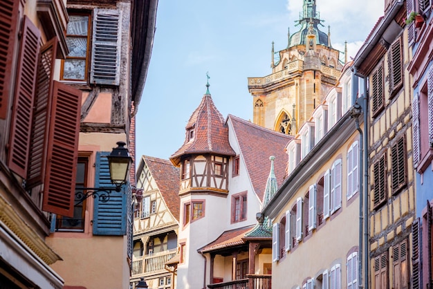 Street view on the beautiful old buildings with cathedral tower in the famous tourist town Colmar in Alsace region, France