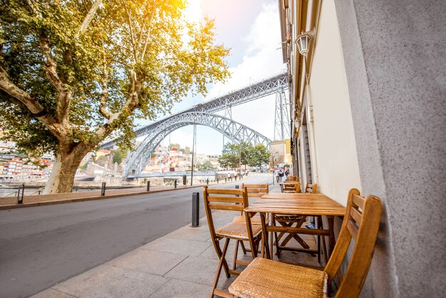 Foto street view con terrazza ristorante e famoso ponte di ferro sullo sfondo nella città di porto, portugal