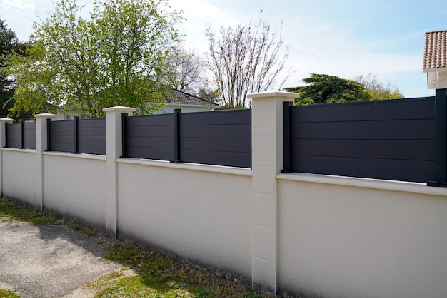 Barriera moderna del muro di strada intorno alla casa di accesso al giardino di protezione della casa