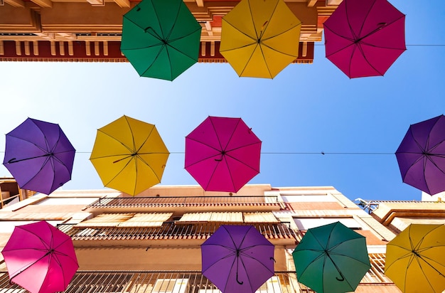 Photo street with bright multicolored umbrellas against the sky with houses