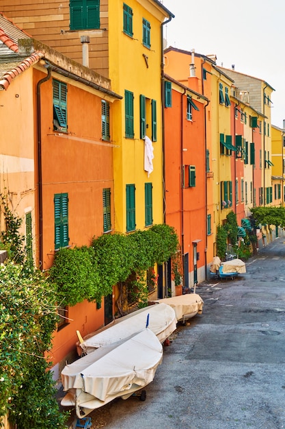 Street with colorful yellow and orange houses in boccadasse district in genoa with parked up fishing boats, italy