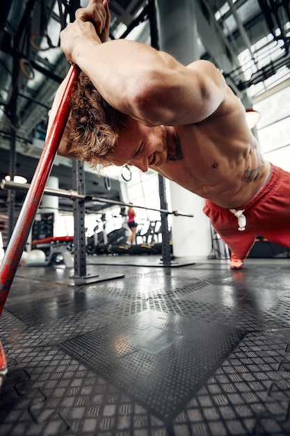 Strength concept male athlete using hammer during fitness
workout fitness man beating rubber tire in gym muscular sportsman
performing intensity training with sledgehammer in sport club