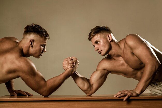 Strength and endurance. Twins men competing till victory. Twins competitors arm wrestling. Men competitors try to win victory or revenge. Strength skills. Revenge in sport.