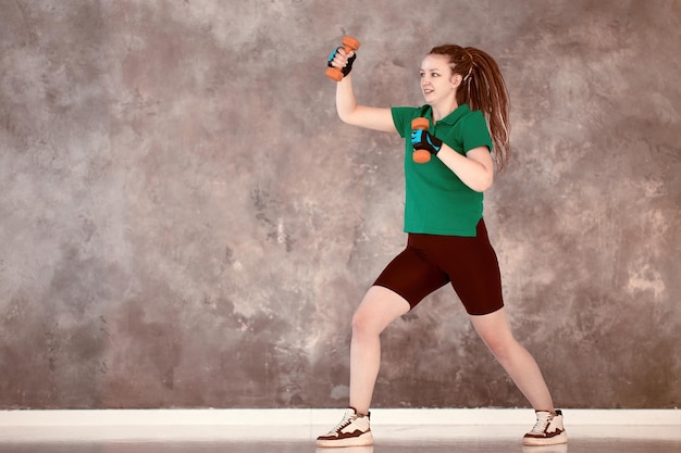 Strength exercise with dumbbells woman boxing in gym