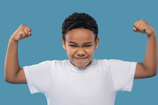 Strength, health. African american boy energetic showing his strength in hands standing tense smiling