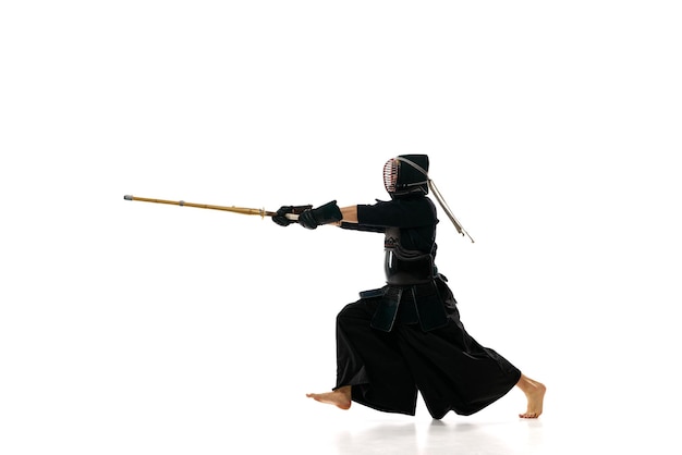 Strength Man professional kendo athlete in black uniform with sword shinai training against white studio background