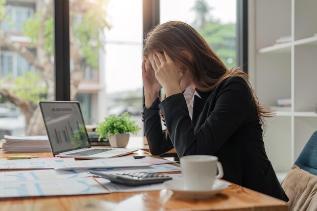 Stress anxiety and burnout with a business woman at work using a laptop while suffering from a headache