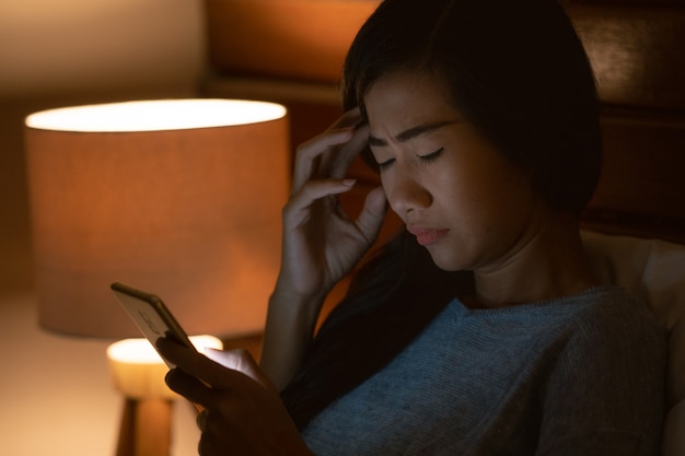 Stress Aziatische vrouw liggend in bed met smartphone