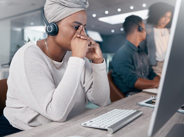 Stress call center and customer service with a woman consultant suffering from burnout or a headache Contact us telemarketing and mental health with a female crm employee at work in the office
