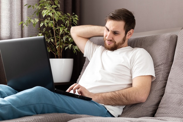 Sottolineare l'uomo cupo caucasico nello stress lavorando da ufficio a casa utilizzando il computer portatile. lavoro a distanza